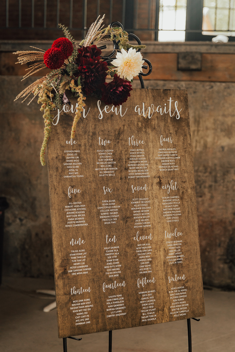 red flowers on corner of rustic wooden seating chart
