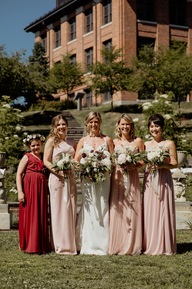 bride stands with bridesmaids in mismatched dresses
