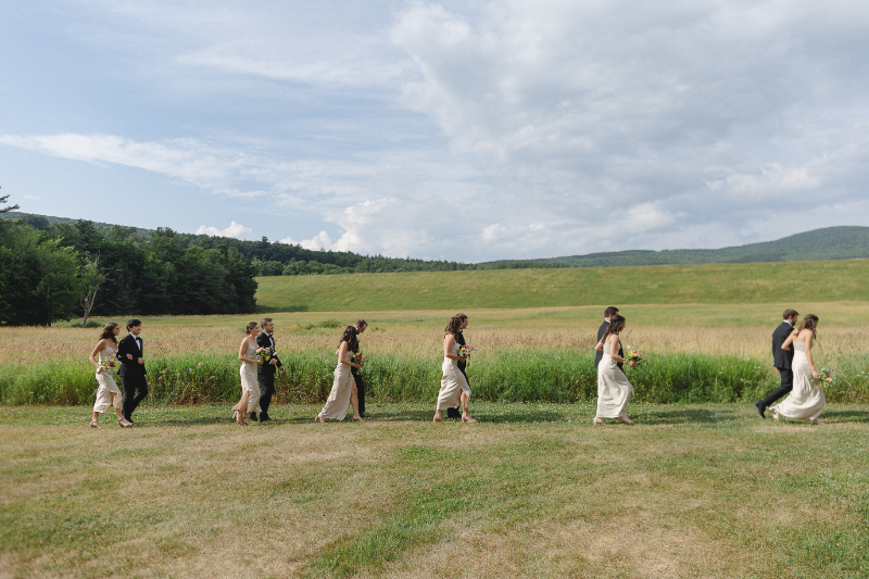 bridesmaids and groomsmen walking in a field