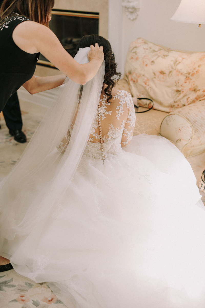 wedding coordinator helps put veil on