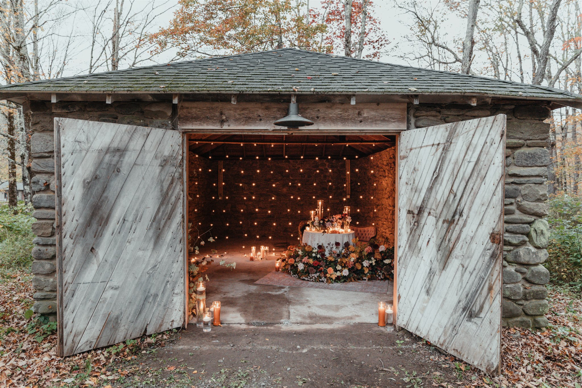 Candlelit table set for two in a rustic barn for the intimate rehearsal dinner.