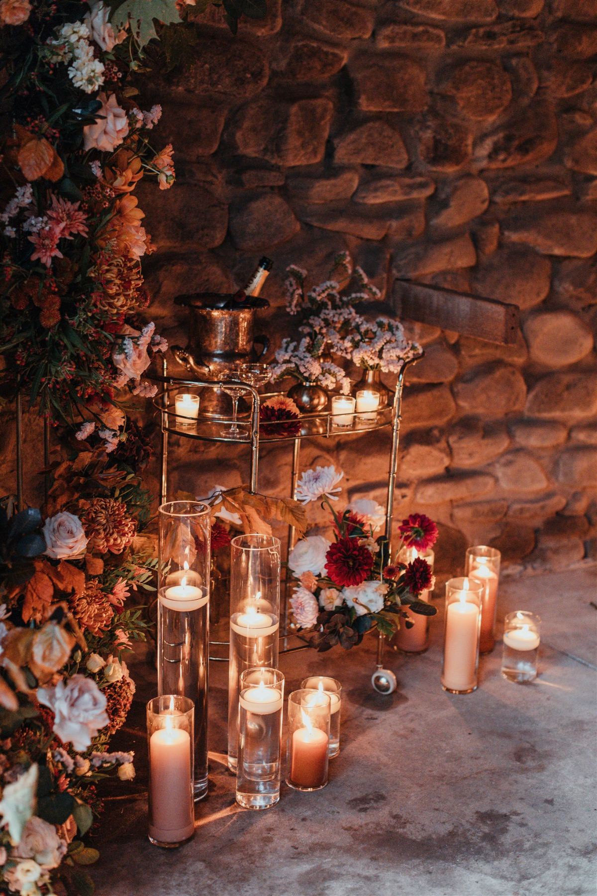 Wooden table adorned with candles and foliage for an intimate dinner.