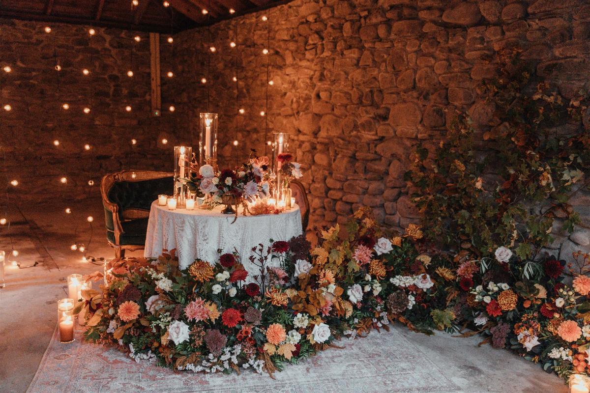 A rustic table with seasonal flowers and personalized place settings for two.