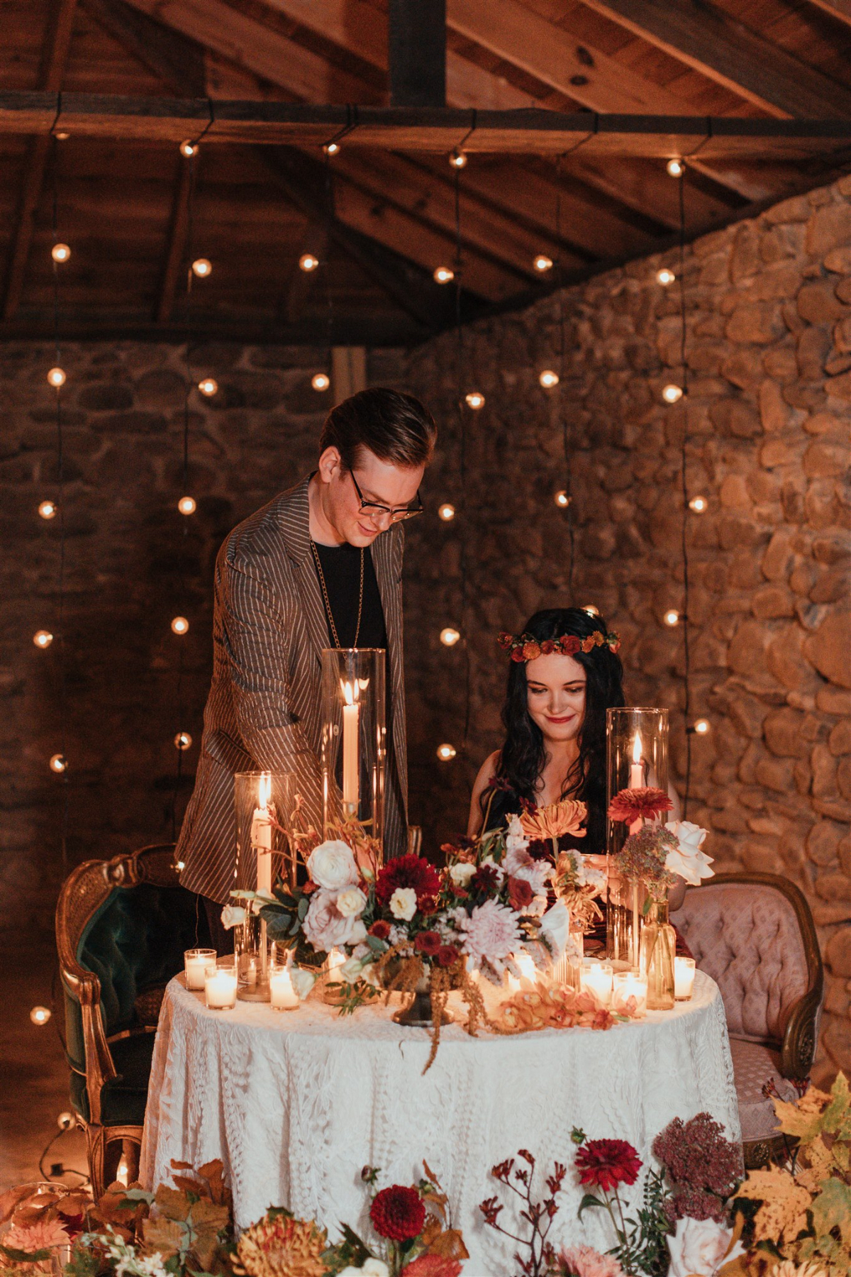 Wooden table adorned with candles and foliage for an intimate dinner.