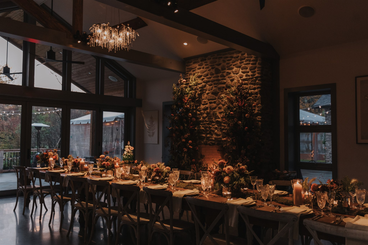 Rustic fall flowers arranged around the reception tables, with moss accents and rich autumn hues creating an elegant woodland tablescape.