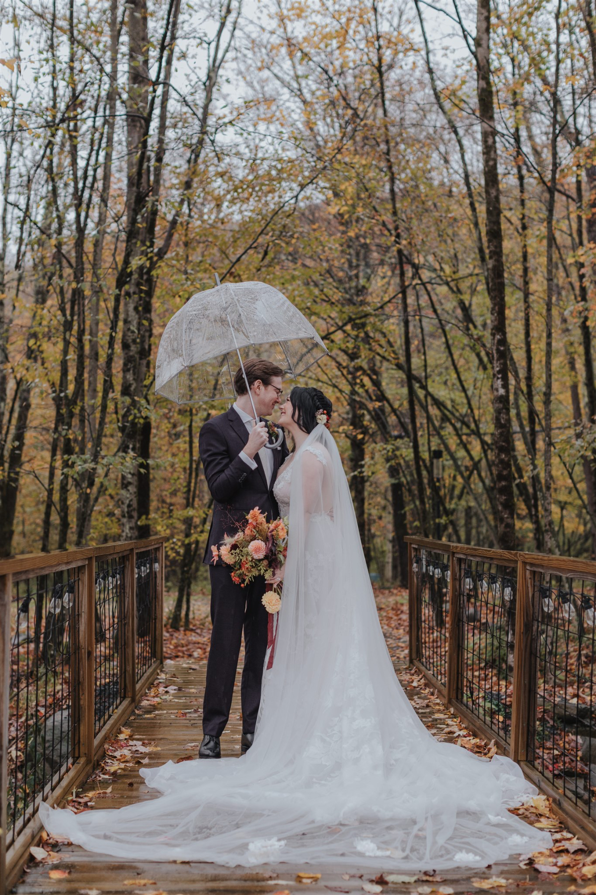 Emily and Greg taking romantic photos on the lush, scenic grounds of Antrim Streamside, surrounded by vibrant fall foliage.