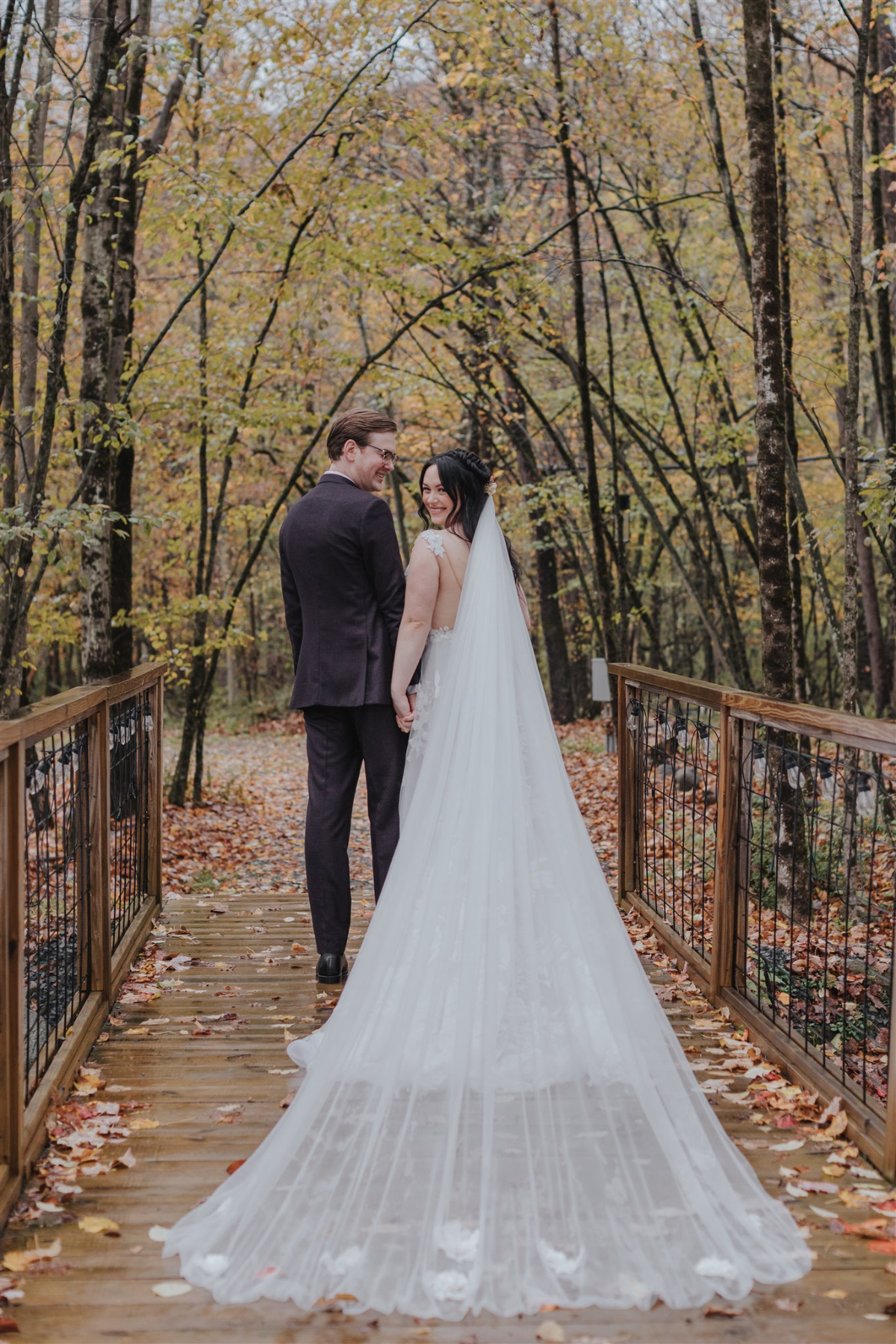 Emily and Greg taking romantic photos on the lush, scenic grounds of Antrim Streamside, surrounded by vibrant fall foliage.