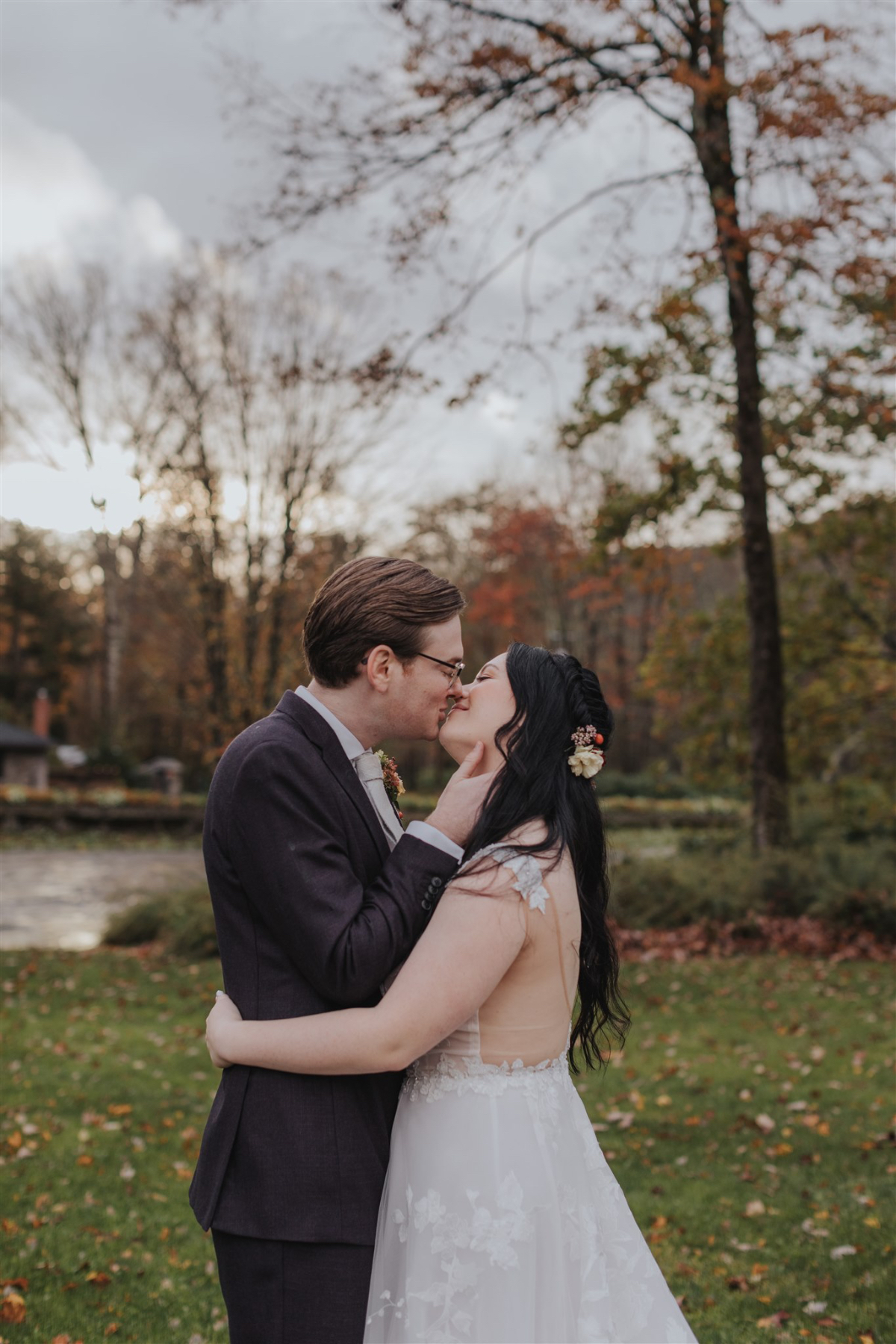 Emily and Greg taking romantic photos on the lush, scenic grounds of Antrim Streamside, surrounded by vibrant fall foliage.