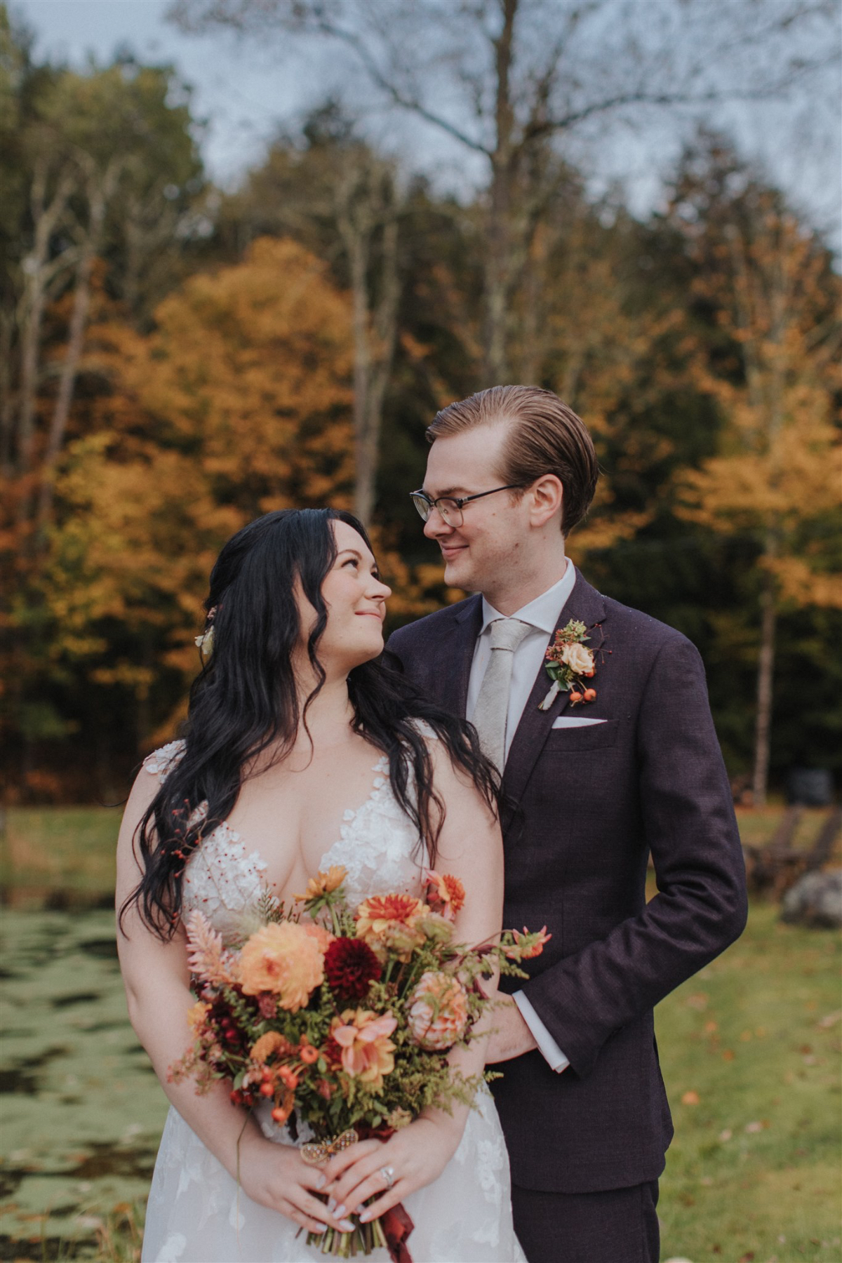 Emily and Greg taking romantic photos on the lush, scenic grounds of Antrim Streamside, surrounded by vibrant fall foliage.