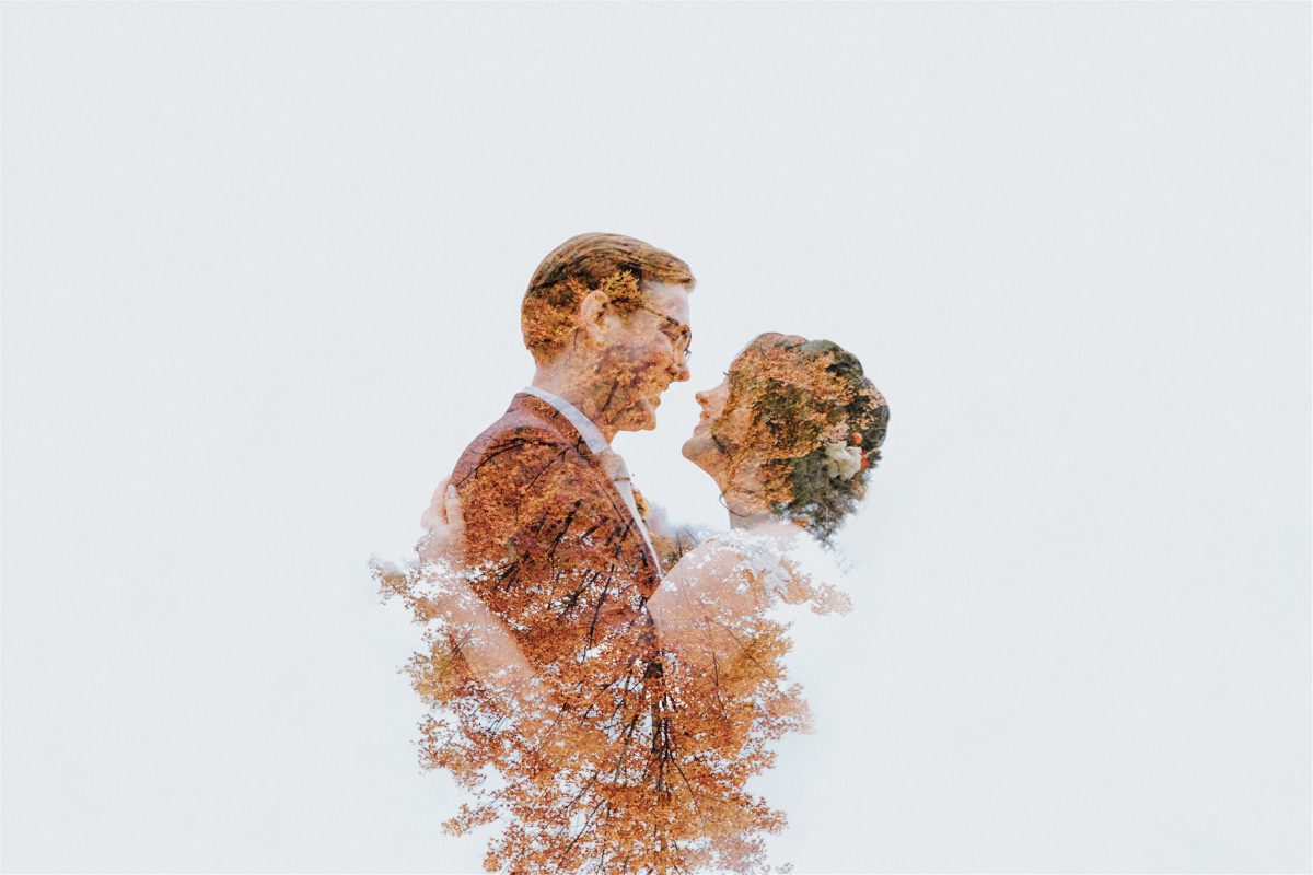 Emily and Greg taking romantic photos on the lush, scenic grounds of Antrim Streamside, surrounded by vibrant fall foliage.
