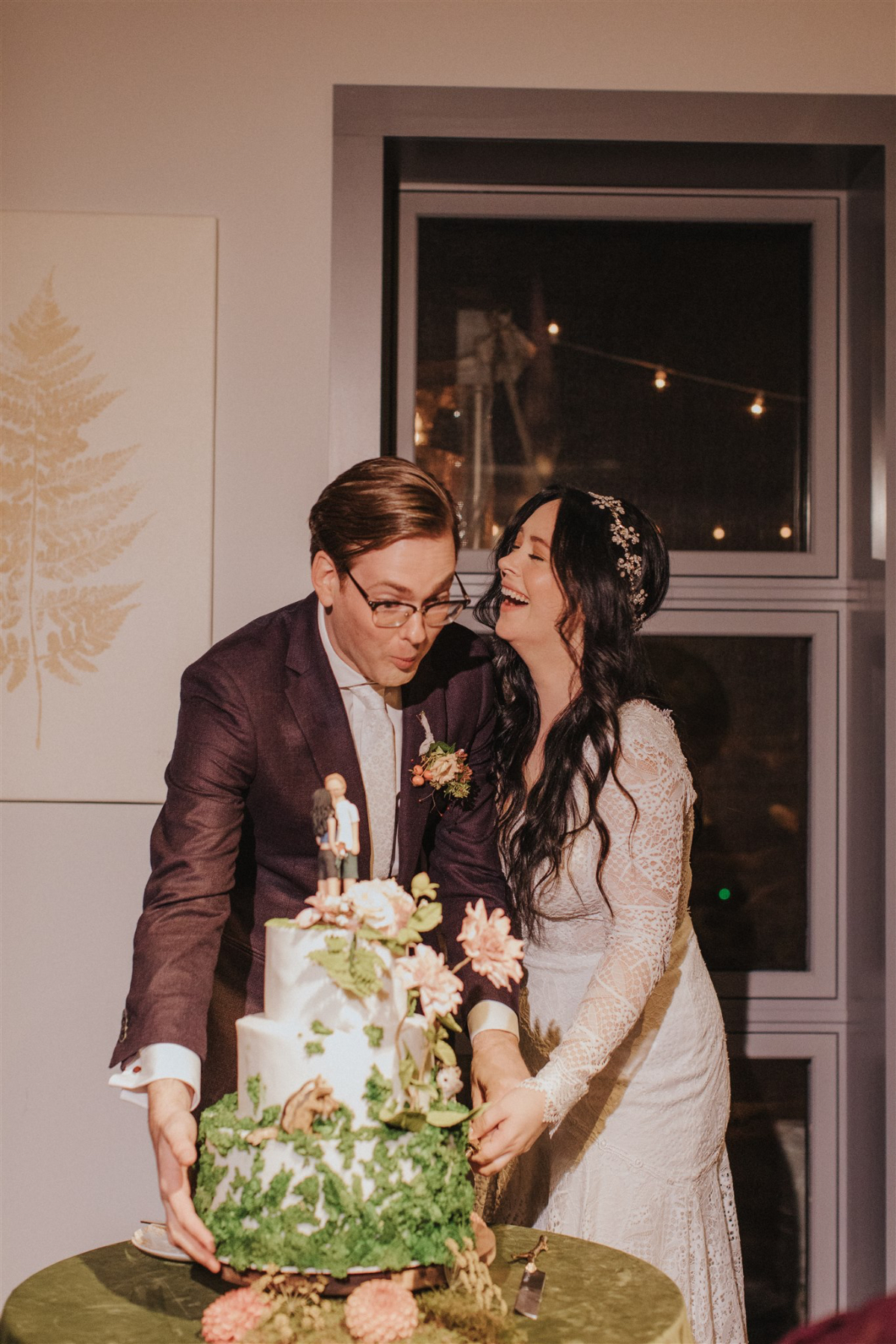 The couple cutting their wedding cake with laughter.