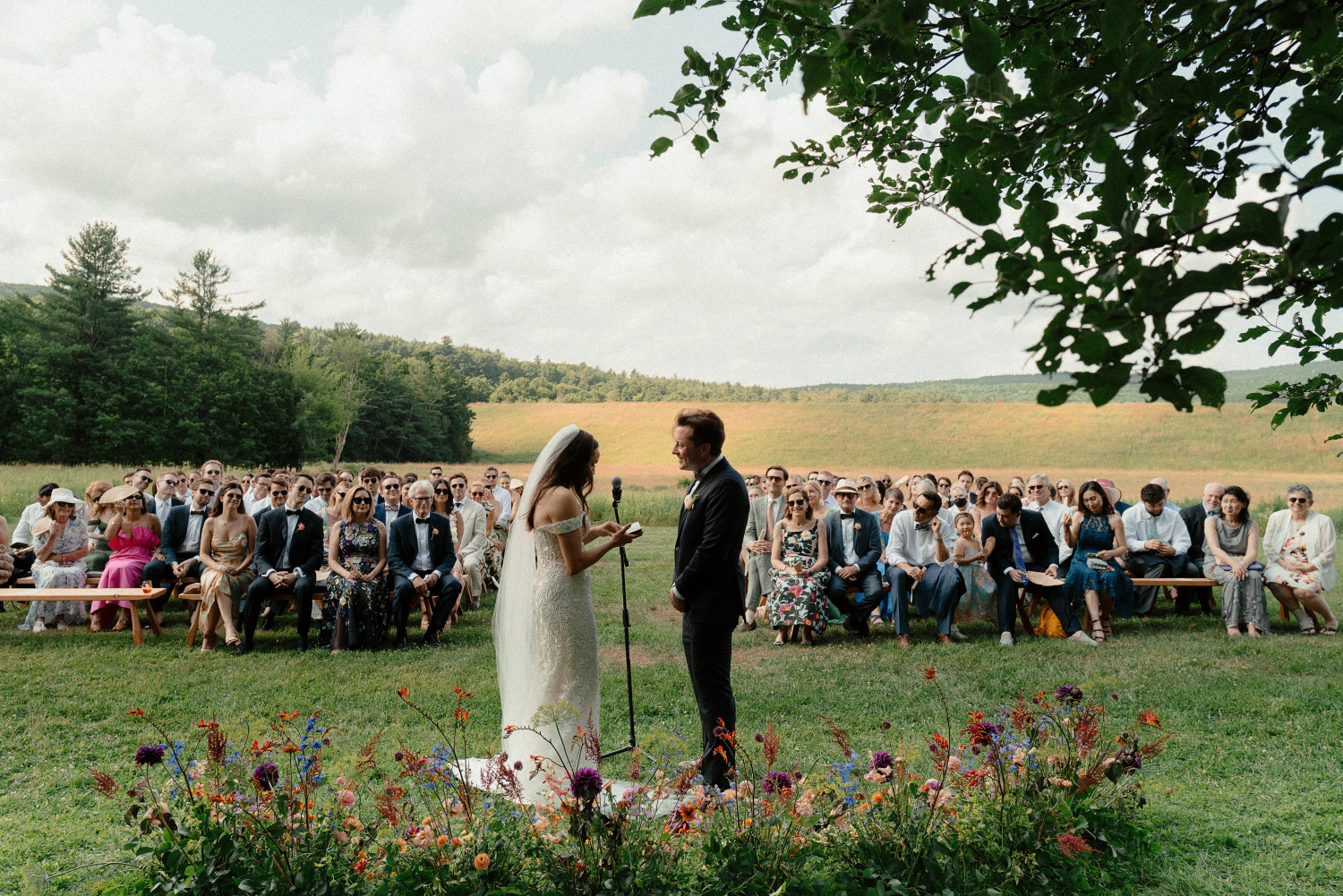bride and groom exchanging vows and wedding guests in the background