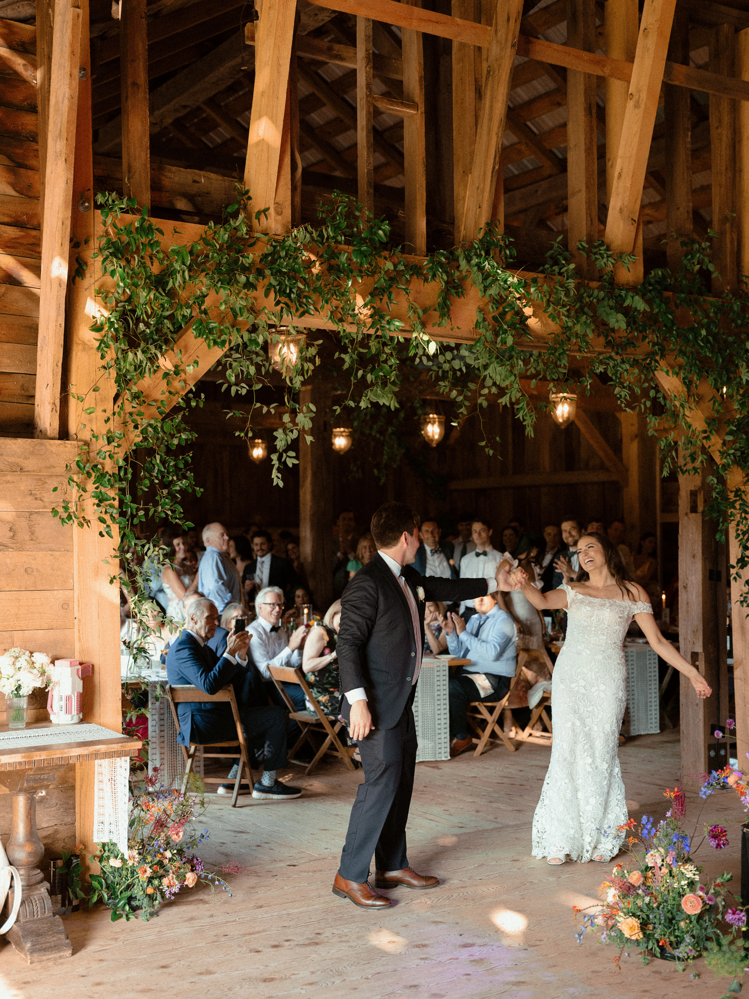 bride and groom first dance during barn wedding and guests watching in the background
