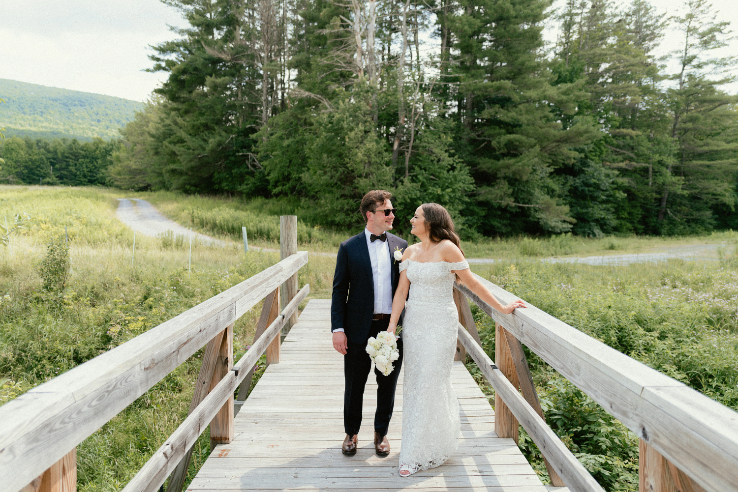 bride and groom outside wedding portraits on a wooden bridge and beautiful lush greenery background