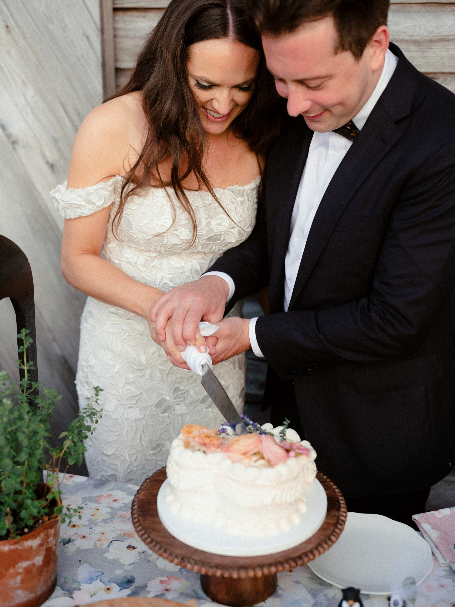 bride and groom cutting their 1 tier cake featuring blush edible flowers