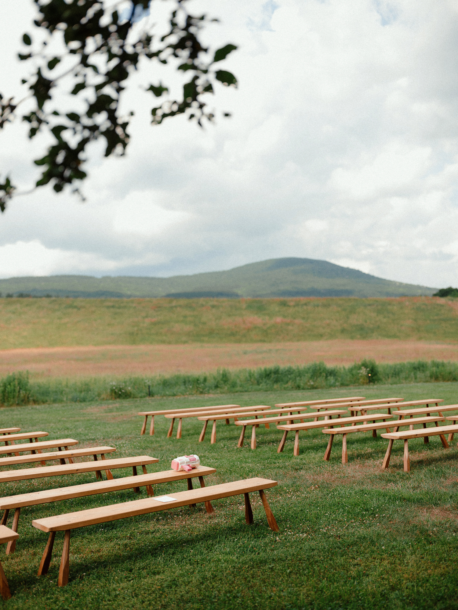 a minimalist rustic ceremony set up of wooden bench seats for guests and a bubble blower sits on one of the benches
