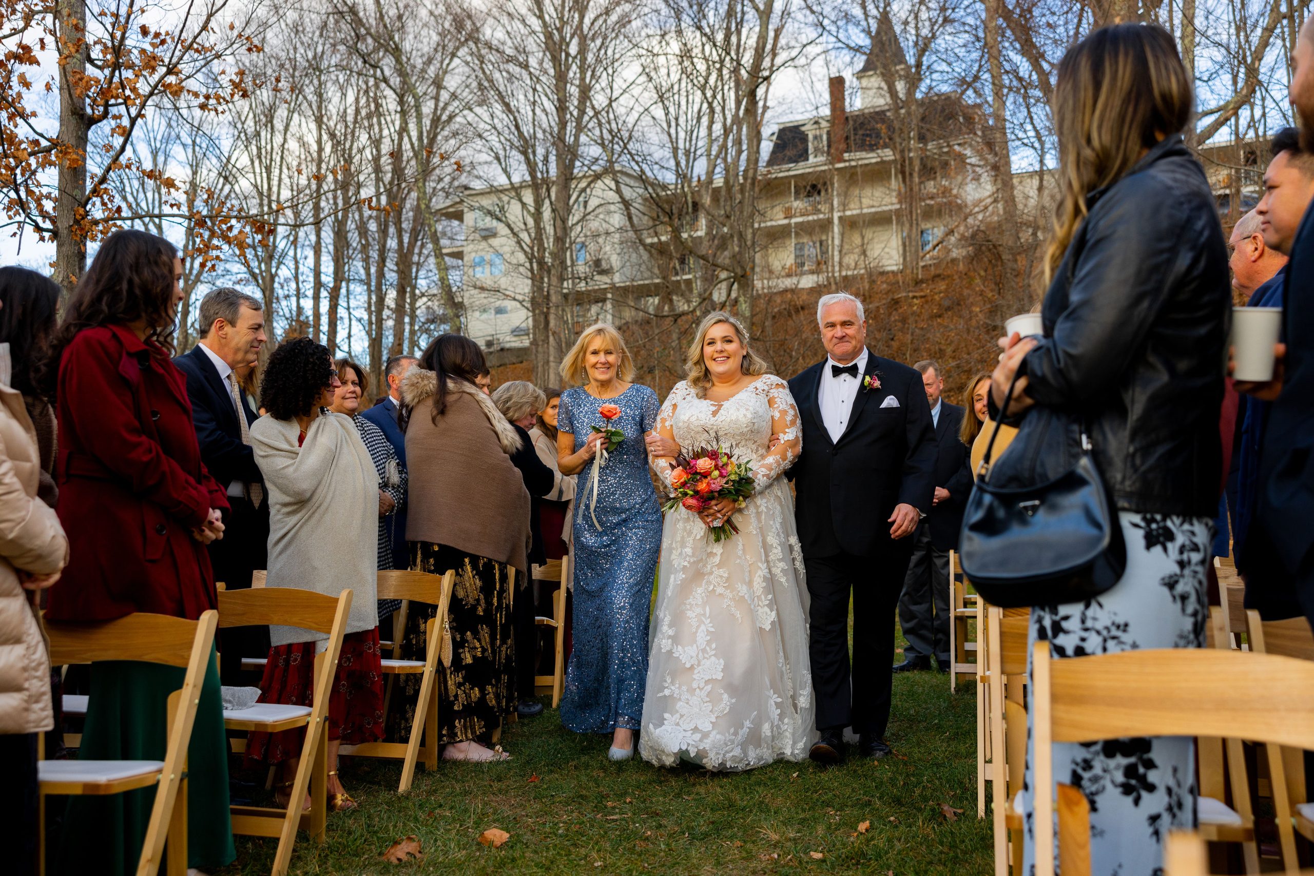talking down the aisle to her groom with mom and dad