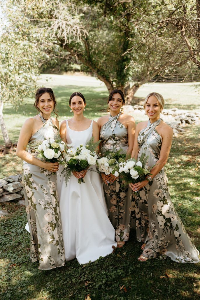 Bride with her bridesmaids in floral dresses, each holding lush bouquets—personalized floral design contributes to the overall cost of home wedding events.