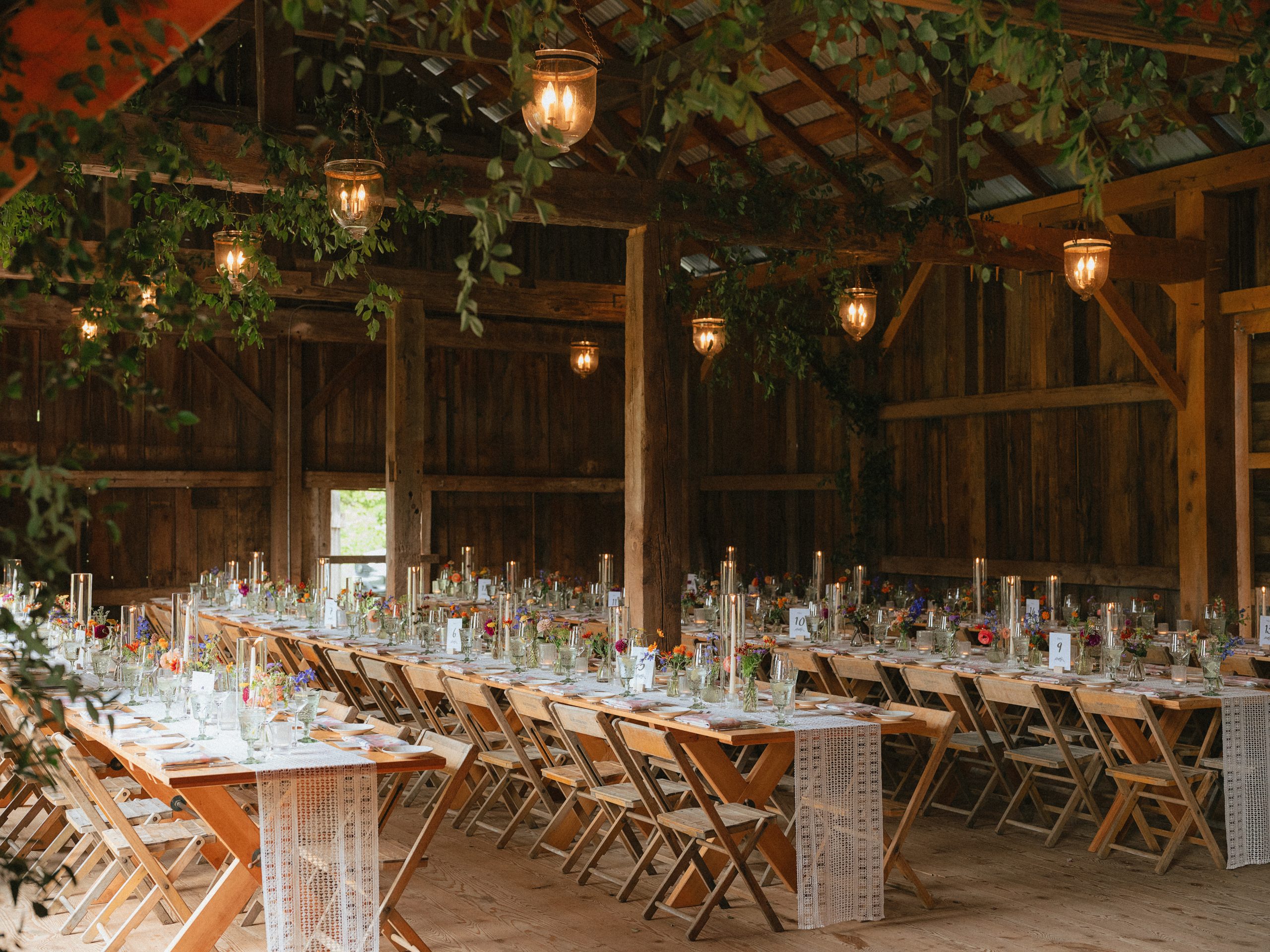 Indoor reception setup with exposed brick, glowing lights, and long wooden tables for an industrial Hudson Valley New York wedding venue
