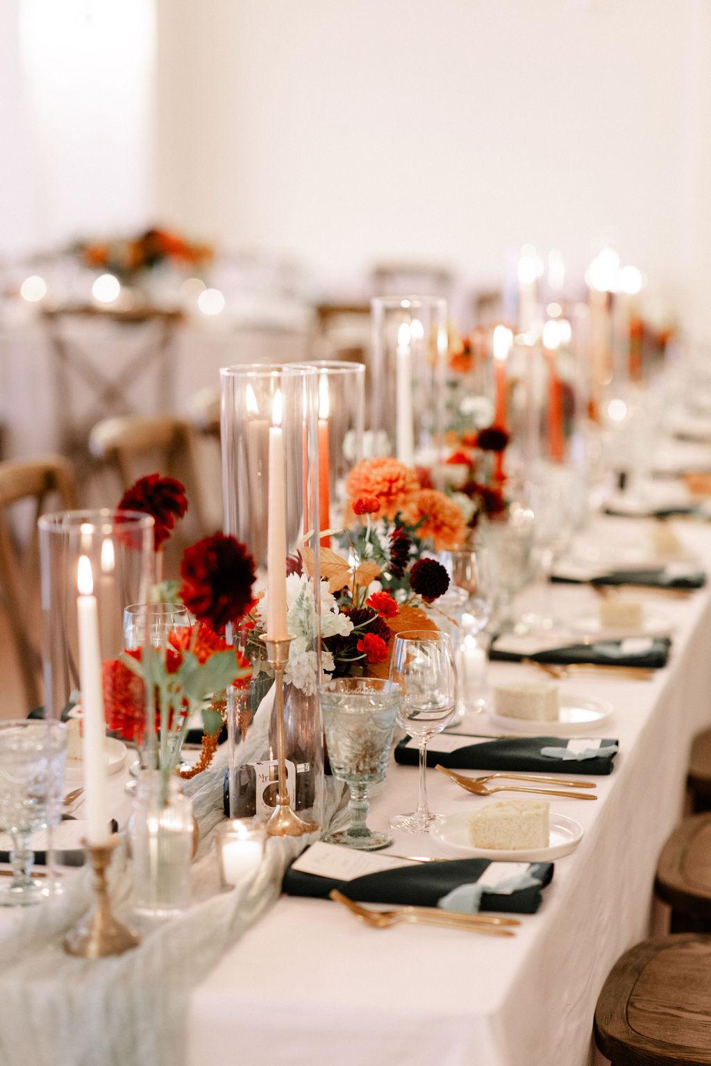 Close-up of fall-inspired wedding tablescape with pillar candles and deep red florals, showcasing personalized event design. wedding planner vs venue coordinator details