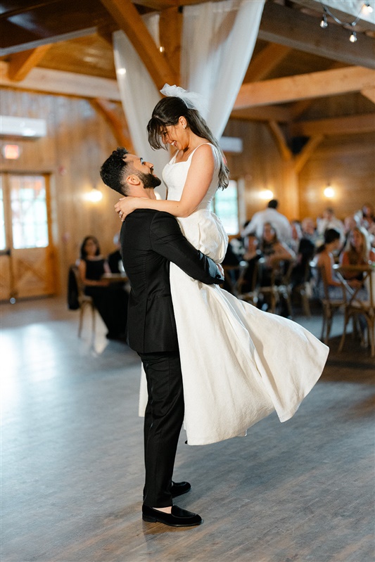 Bride and groom share an emotional first dance inside a barn-style venue, a timeless moment highlighted in the best wedding media storytelling.