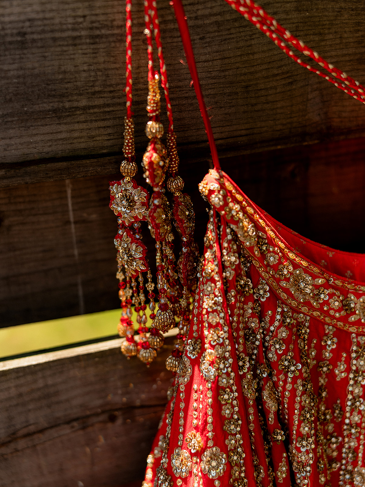 Close-up detail of red bridal lehenga tassels embroidered with gold, captured at an Indian wedding.