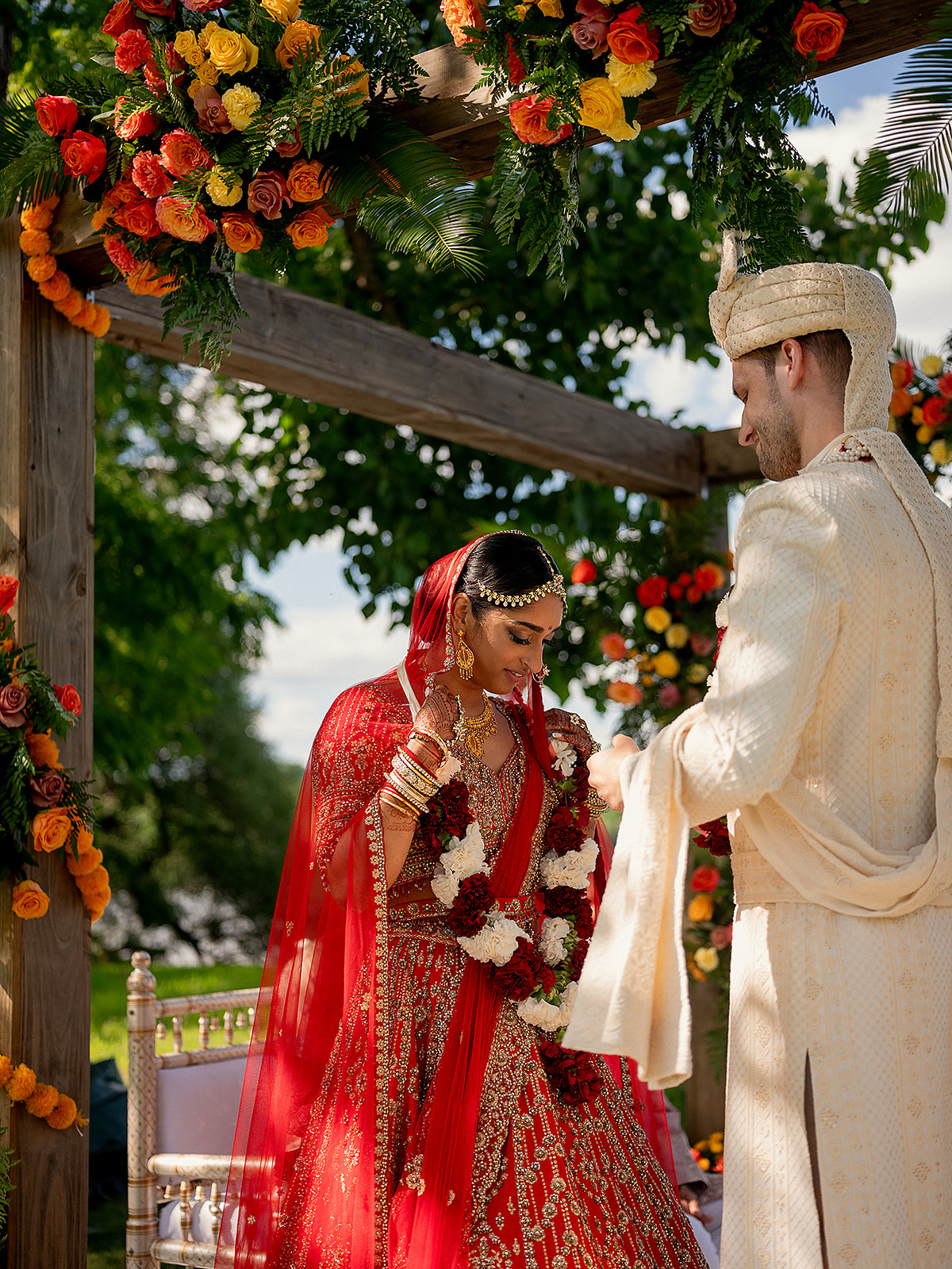 Bride and groom sharing a heartfelt moment beneath lush floral arrangements during Hindu wedding.