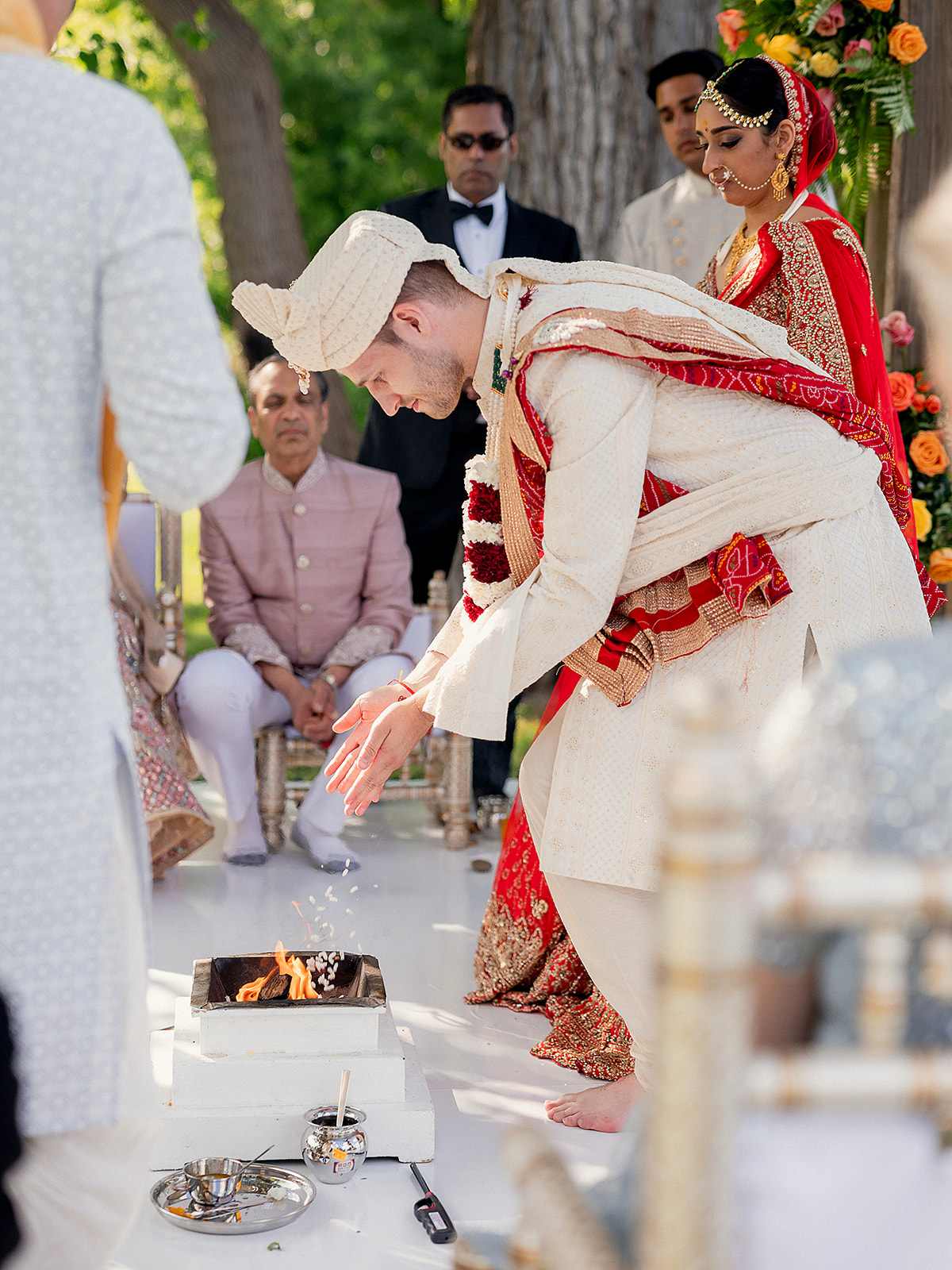 Groom offering rice into the ceremonial fire during Hindu wedding rituals at the mandap.