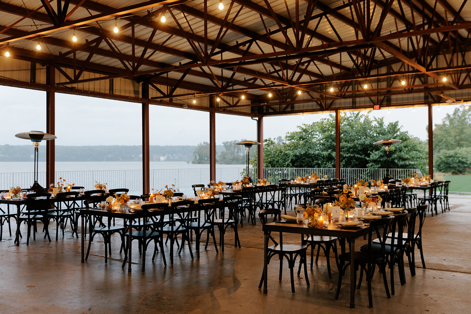 Candlelit reception tables arranged in an open-air pavilion overlooking the Hudson River at a Hudson Valley wedding venue with accommodations.