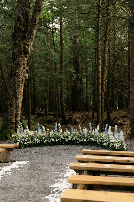 Wooded ceremony setup with floral arrangements and rustic benches at a Hudson Valley wedding venue with accommodations.