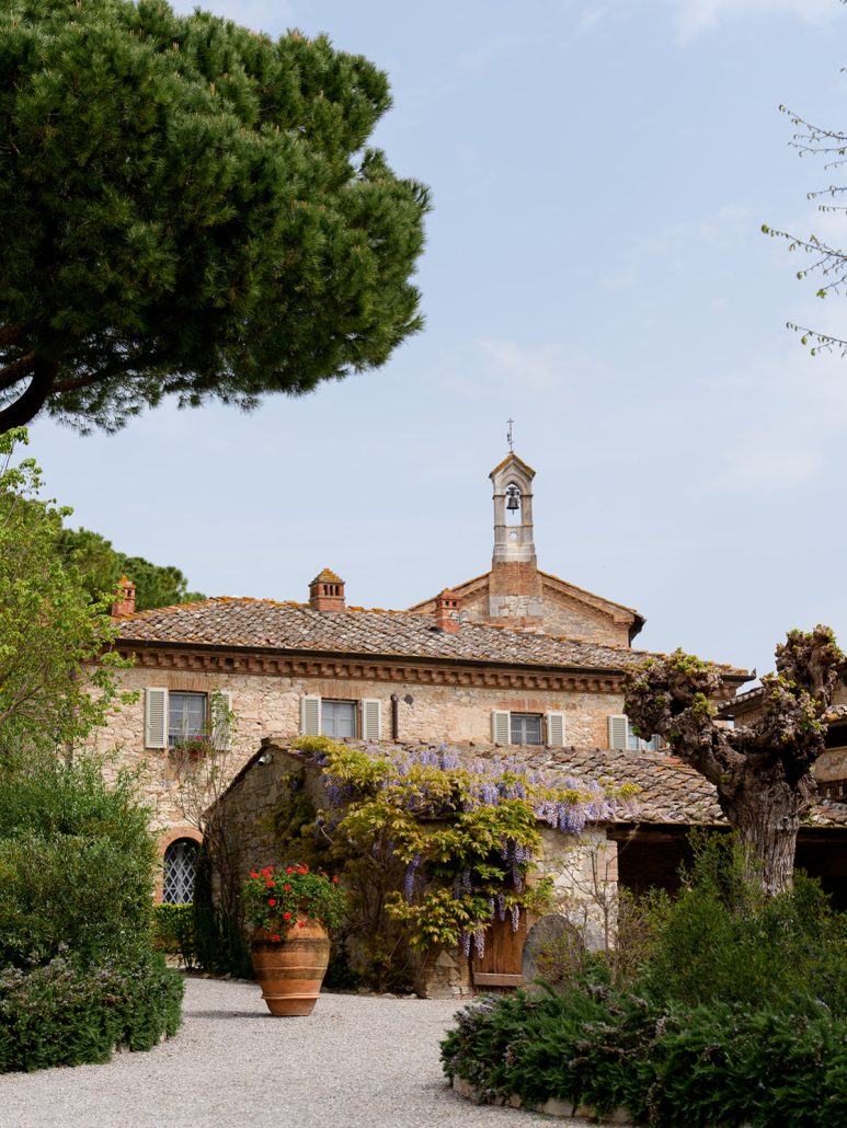 Romantic Tuscan villa courtyard with blooming wisteria, terracotta pots, and rustic charm, perfect for wedding photography.