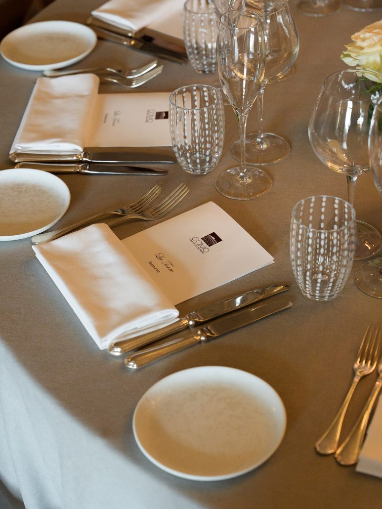 Elegant table setting at COMO Castello Del Nero featuring menus, fine glassware, and chic neutral linens for a Tuscany wedding reception.