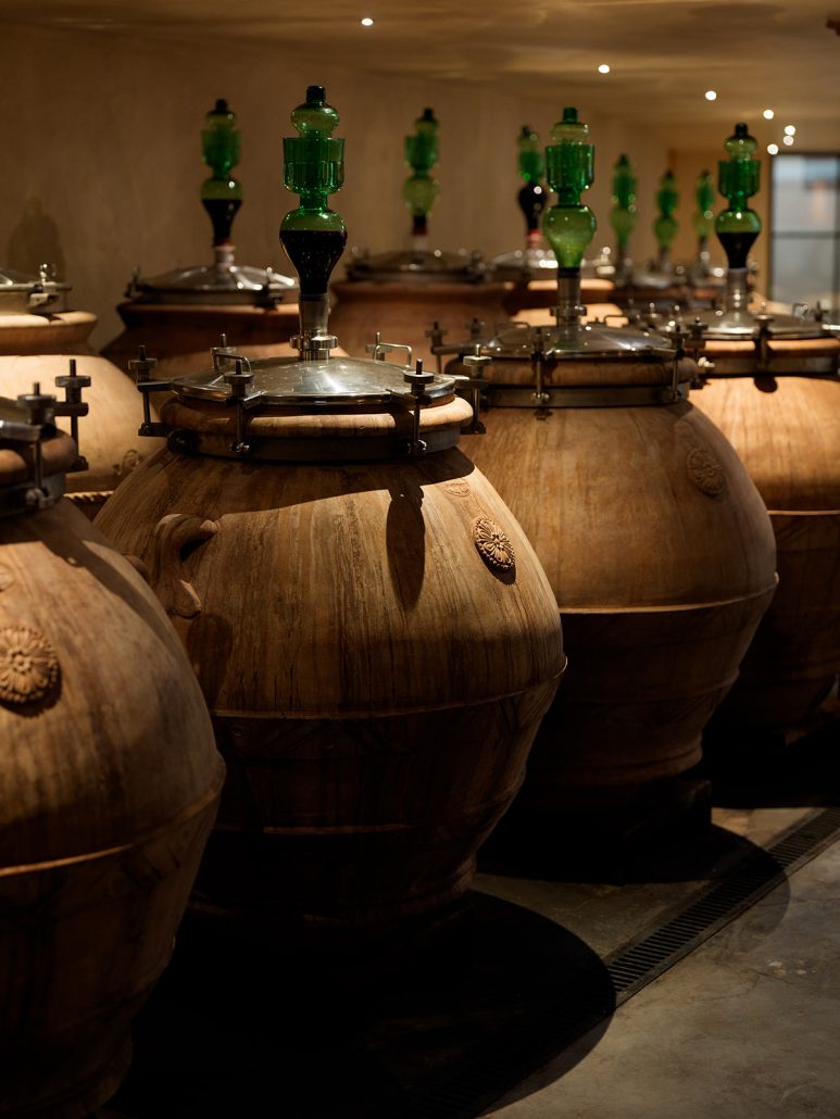 Traditional terracotta wine vessels with green glass tops inside Il Borro’s cellar, highlighting its unique Tuscan character.