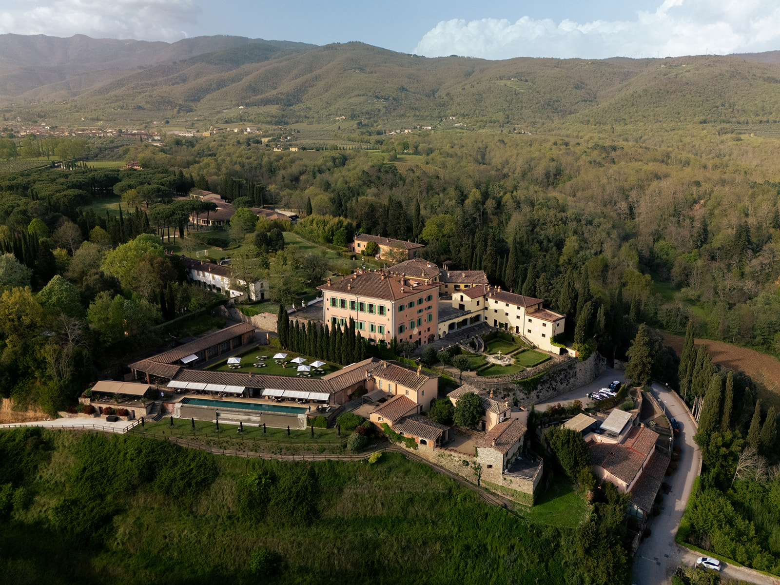 Aerial view of Il Borro estate surrounded by vineyards and rolling hills, an idyllic setting for weddings in Tuscany.
