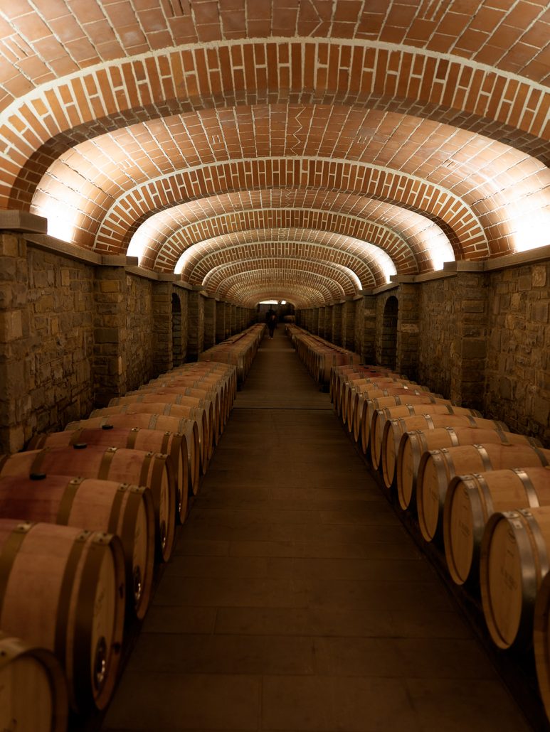 A vaulted wine cellar lined with oak barrels at Il Borro, one of the most romantic wedding venues in Tuscany for wine lovers.