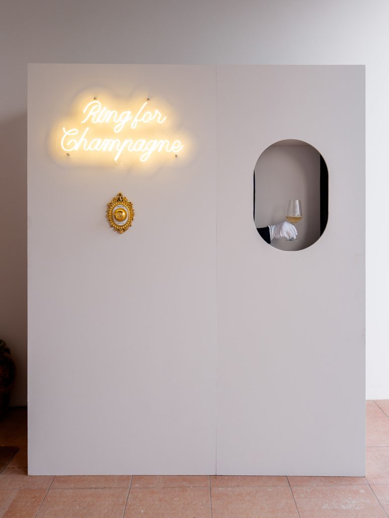 Fun champagne station at Viesca Toscano wedding venue in Tuscany with a neon sign reading “Ring for Champagne” and a gloved hand serving a glass.