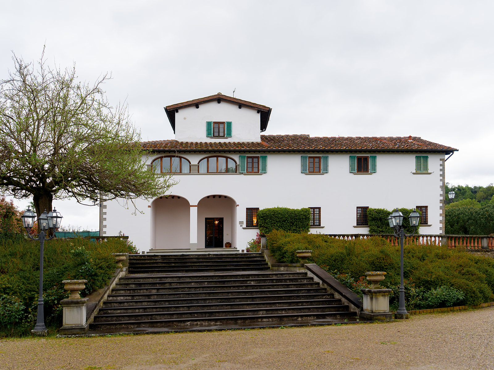 Elegant white villa at Viesca Toscano wedding venue in Tuscany, with stone steps and traditional green shutters, ideal for a destination celebration.