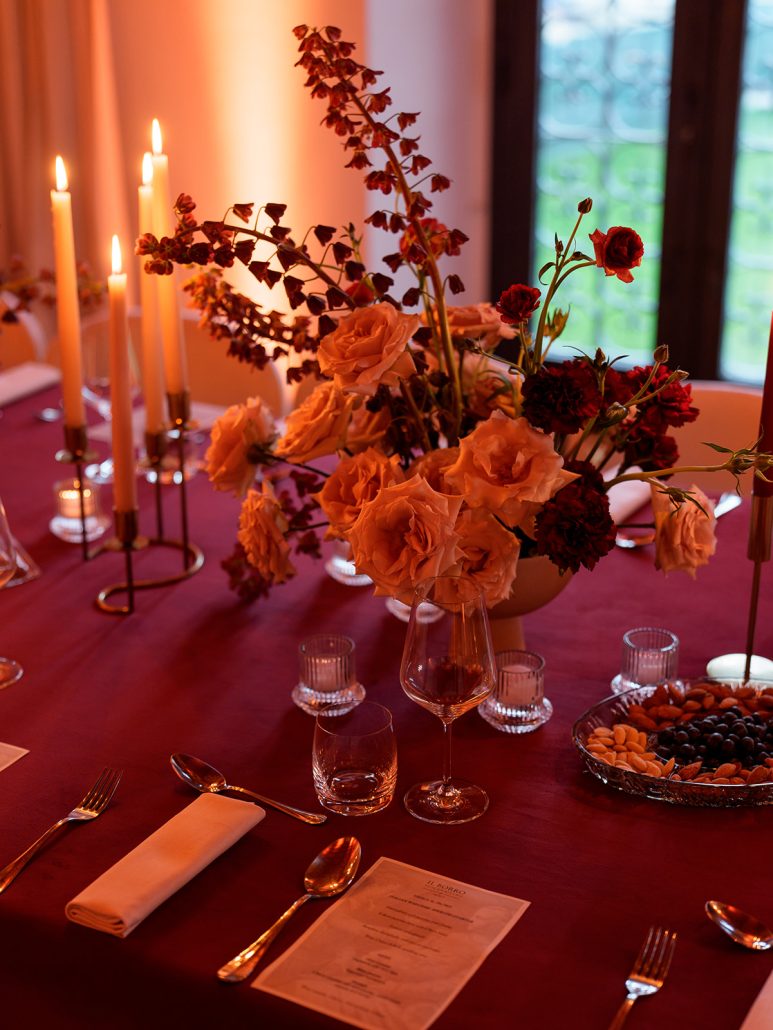 Elegant wedding dinner setup in Tuscany with burgundy tablecloths, candlelight, and floral centerpieces at Viesca Toscano, perfect for intimate receptions.