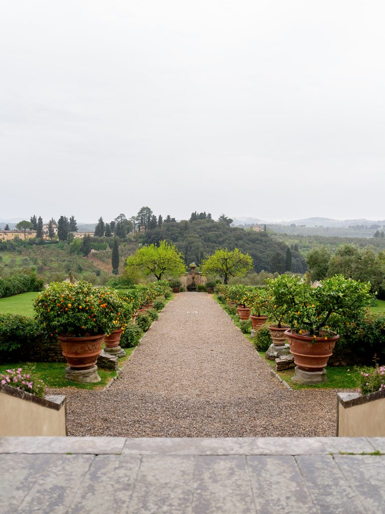 Garden path lined with terracotta planters and orange trees at Villa Medicea di Lilliano, a romantic wedding venue in Tuscany.