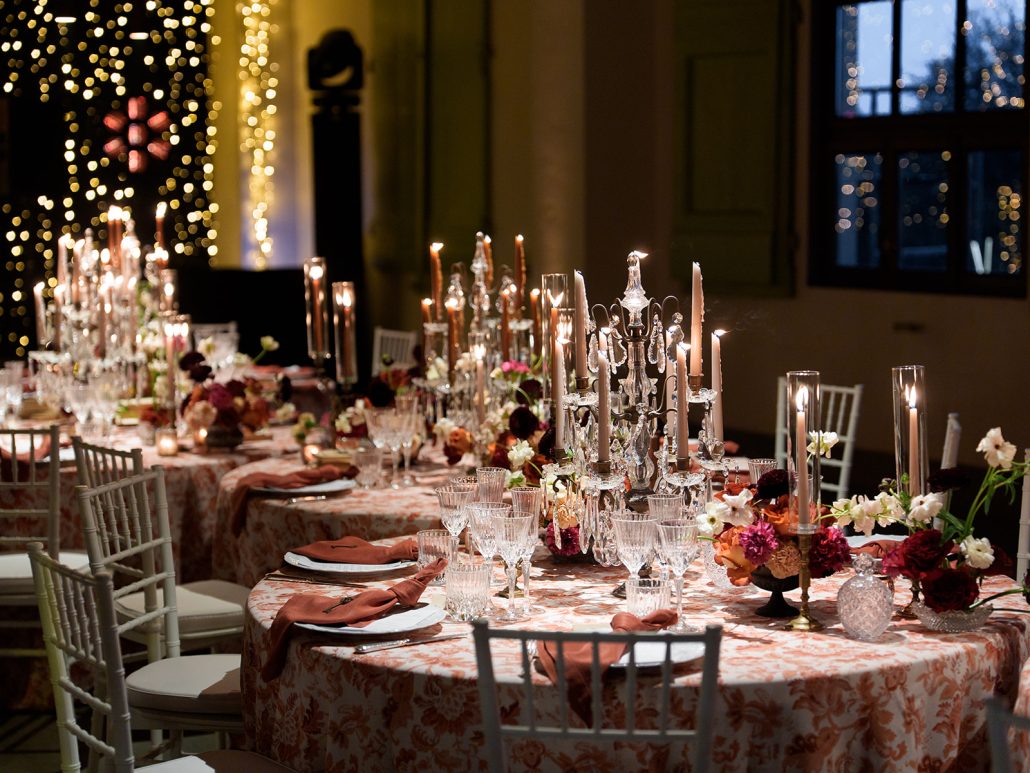 Elegant candlelit wedding reception setup at Villa Medicea di Lilliano with floral centerpieces, crystal glassware, and patterned linens.