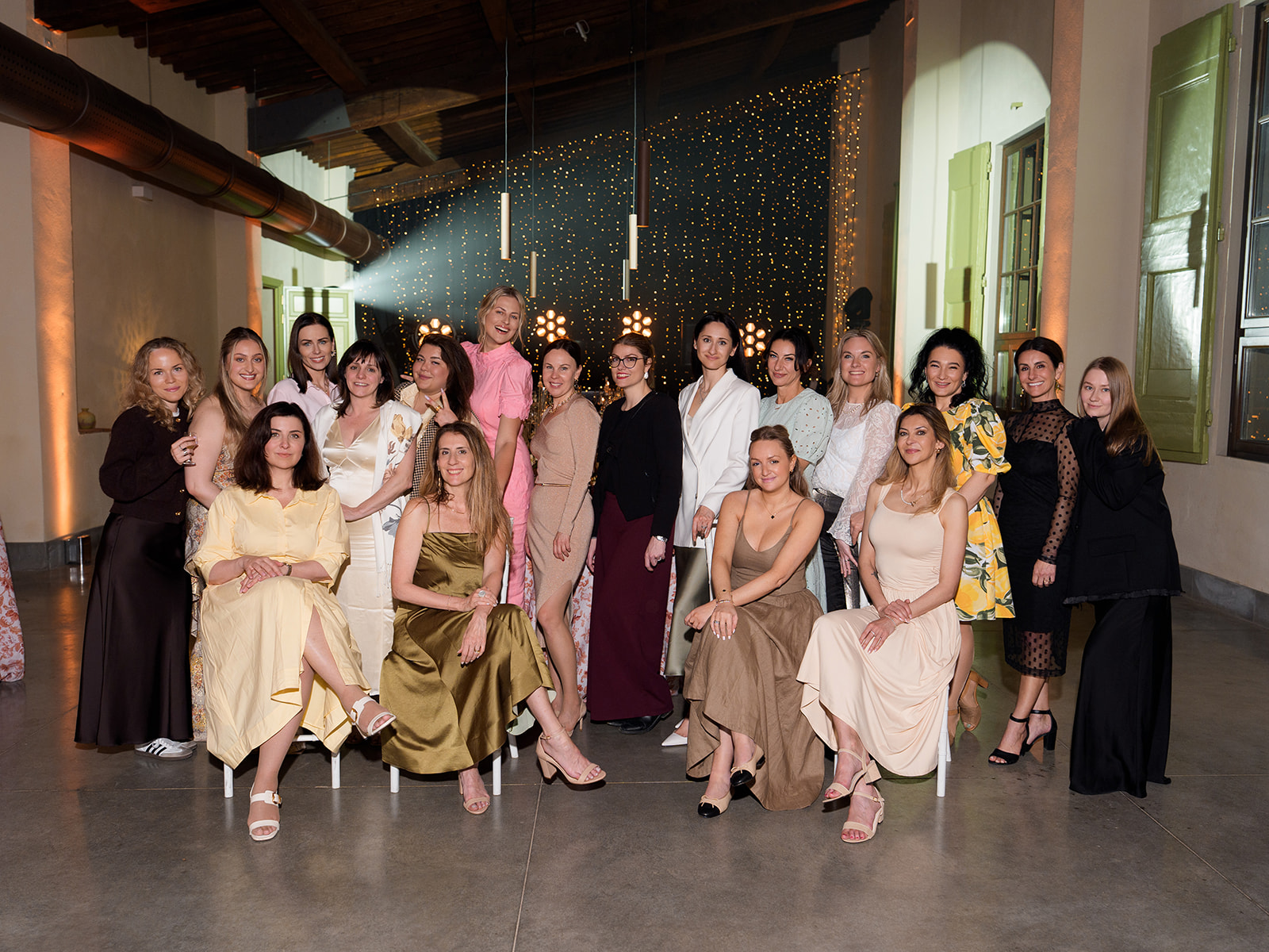 Group of women gathered at a wedding planning event in Tuscany, set against twinkling lights at a luxury Italian wedding venue.