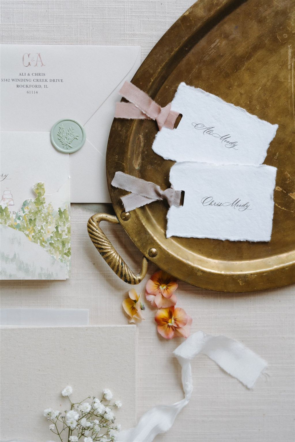 Elegant gold tray with handmade wedding escort cards, velvet ribbon, and wax-sealed envelopes.