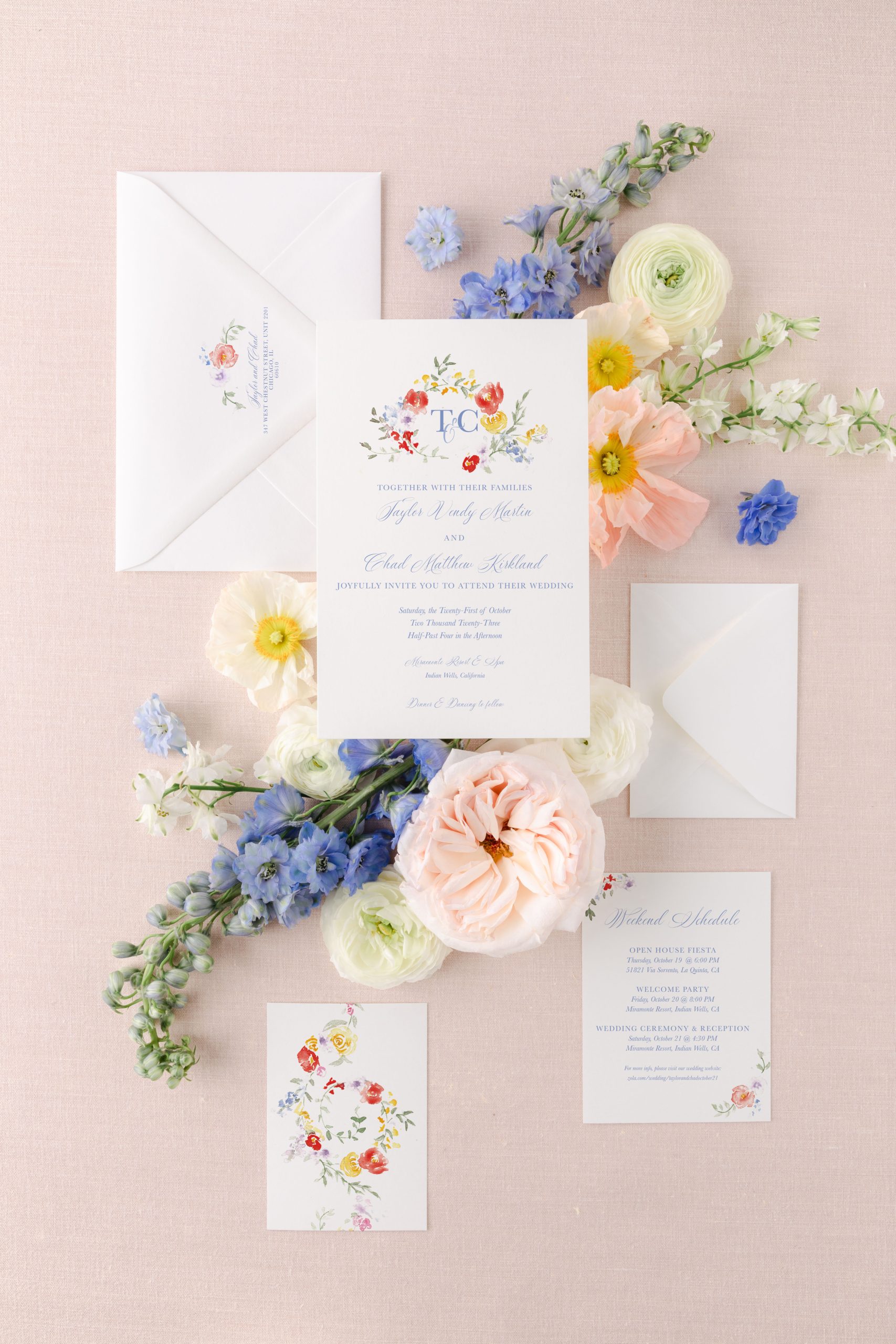 Mailing wedding invitations featuring a custom floral crest, elegant serif font, and soft pink styling.