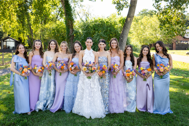 Bride surrounded by bridesmaids in soft pastel gowns during their summer Hudson River wedding celebration.