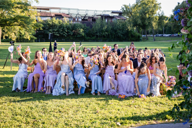 Wedding guests and bridesmaids cheering and raising bouquets after the ceremony