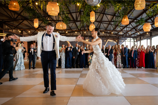 Groom twirling the bride across the dance floor during their summer Hudson River wedding reception.