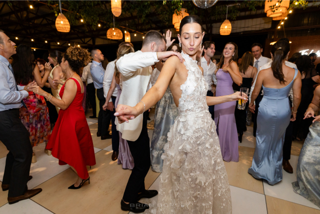 Bride dancing energetically on the dance floor surrounded by guests at a summer Hudson River wedding at Hutton Brickyards.