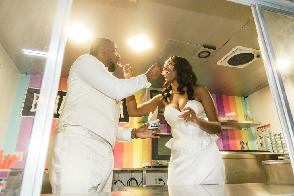 Couple sharing ice cream cones from a vintage truck at their outdoor wedding.
