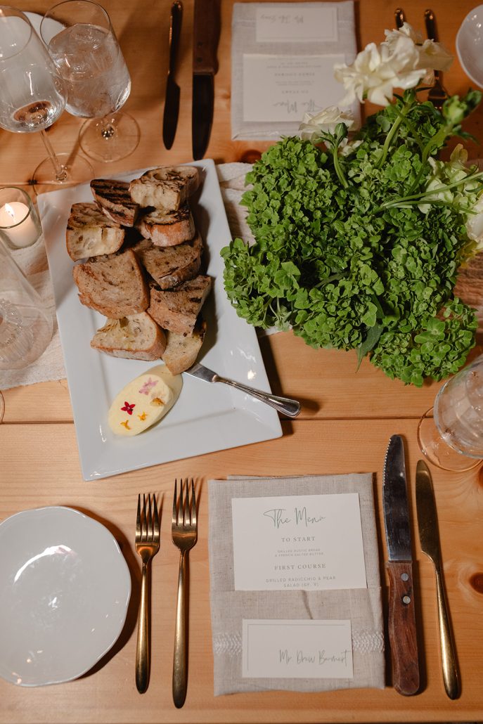 Artisan bread with hand-whipped butter and herbs, styled as part of a refined wedding food tablescape.