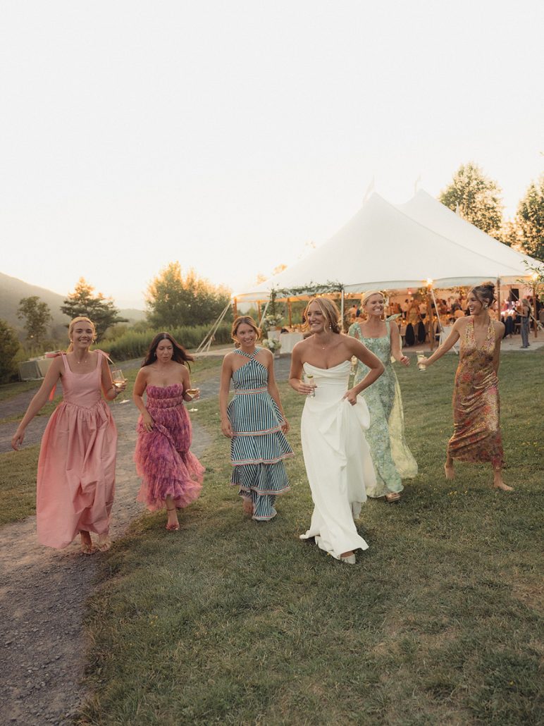 Bridesmaids laughing and walking with the bride near the reception tent during a Scribner’s Catskill Lodge wedding.